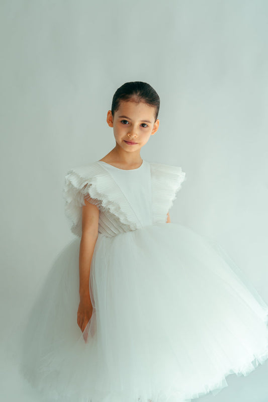 A young girl wearing a white, floral dress with voluminous sleeves and skirt