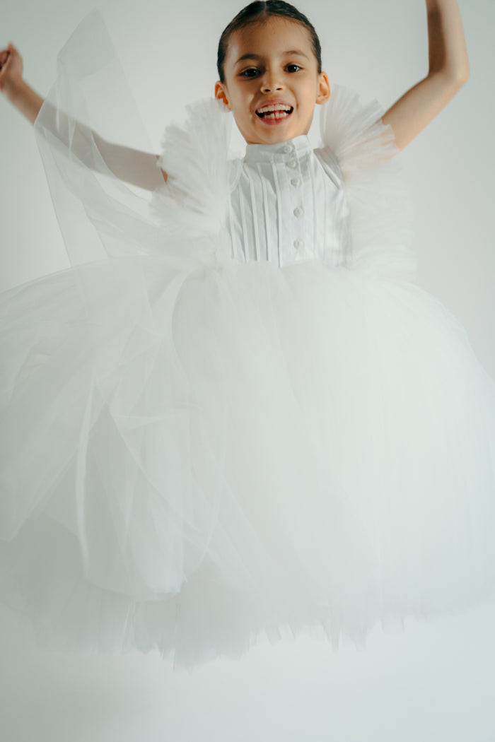 Girl in the white francine tulle dress jumping happily
