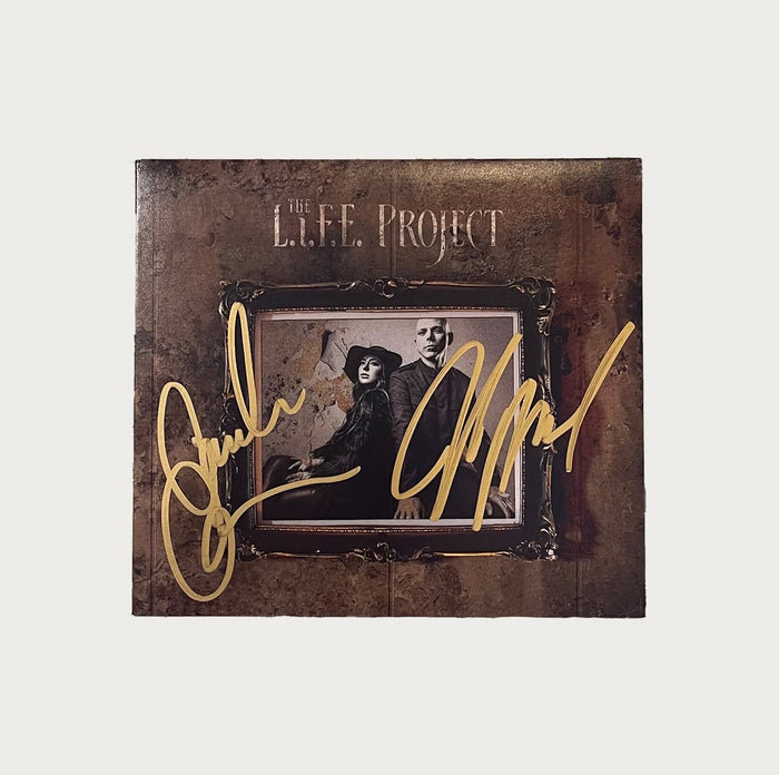 A signed The L.I.F.E. Project album cover featuring a sepia-toned image of a man and woman in vintage clothing, with bold gold signatures blazing across the front.