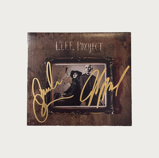 A signed The L.I.F.E. Project album cover featuring a sepia-toned image of a man and woman in vintage clothing, with bold gold signatures blazing across the front.
