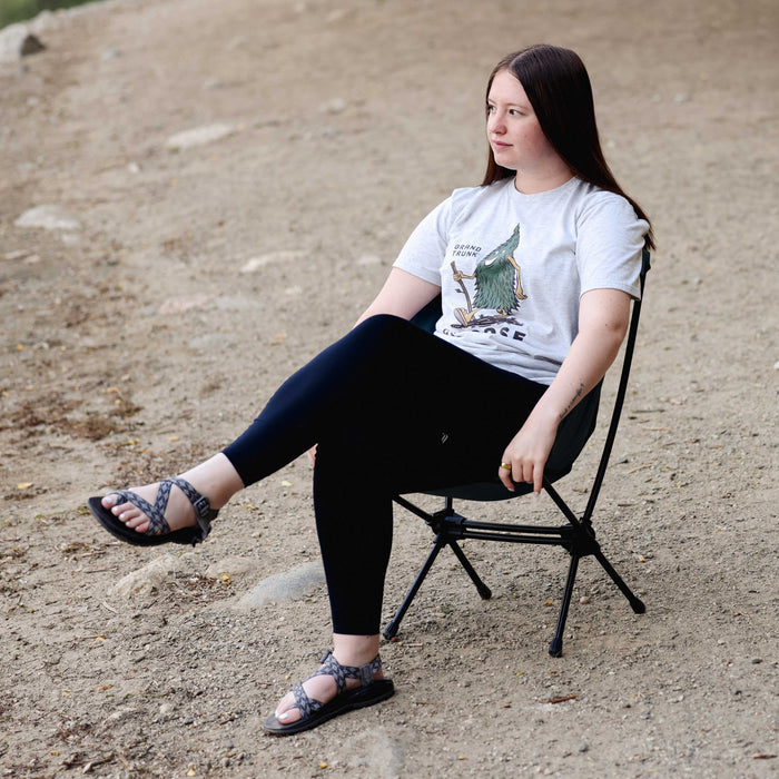 Person sitting on a folding chair outdoors wearing a graphic t-shirt.