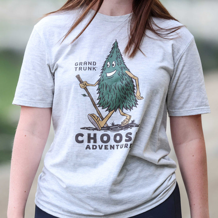Person wearing a gray t-shirt with a cartoon tree character and text 'Grand Trunk Choose Adventure'.