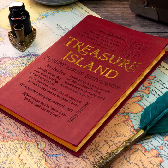 Red leather-bound book titled 'Treasure Island' by Robert Louis Stevenson on a world map with a quill pen. The side of the book is yellow.