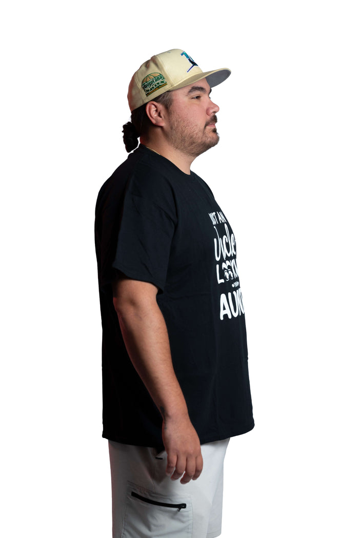 Man wearing a black “Uncle Looking for Auntie” graphic tee and cap side view