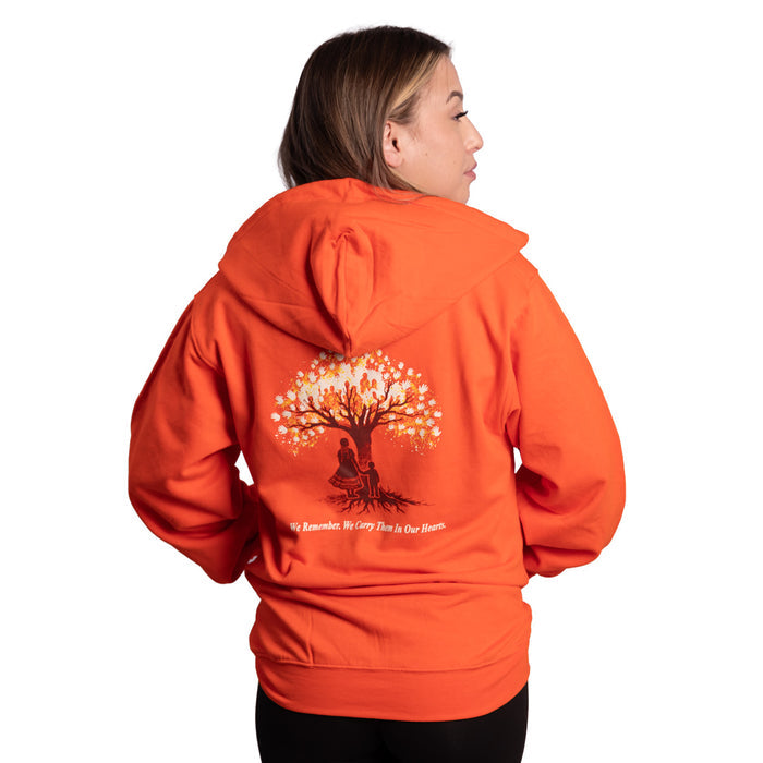 Person wearing an orange hoodie with a tree design on the back, on a white background